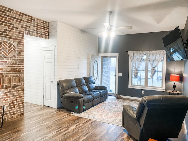 living room featuring brick wall, ceiling fan, and light hardwood / wood-style flooring