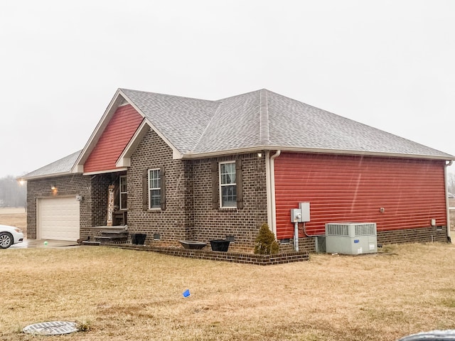 view of side of property featuring cooling unit, a garage, and a yard