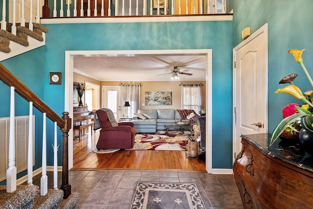 tiled foyer entrance with crown molding, ceiling fan, a textured ceiling, and a high ceiling