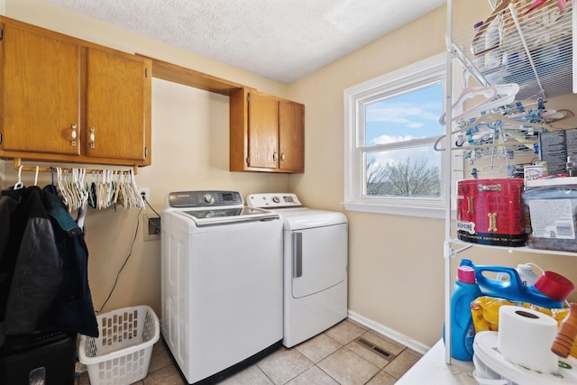 laundry room featuring cabinets, separate washer and dryer, light tile patterned floors, and a textured ceiling