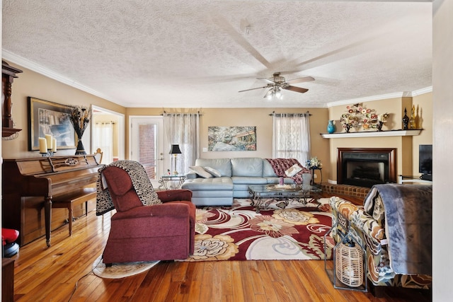 living room with wood-type flooring, crown molding, a textured ceiling, and a fireplace