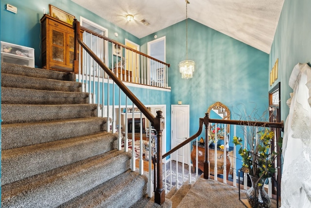 staircase with an inviting chandelier, high vaulted ceiling, and carpet