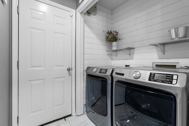 clothes washing area featuring wooden walls and washing machine and dryer