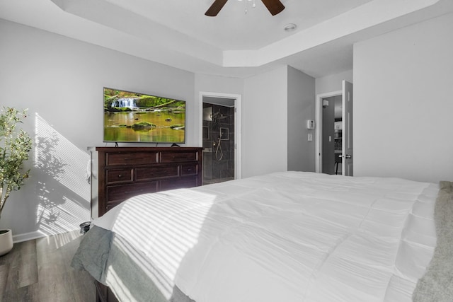 bedroom with hardwood / wood-style floors, a tray ceiling, and ceiling fan