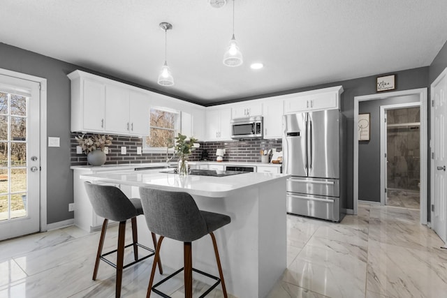 kitchen with appliances with stainless steel finishes, a center island, pendant lighting, and white cabinets