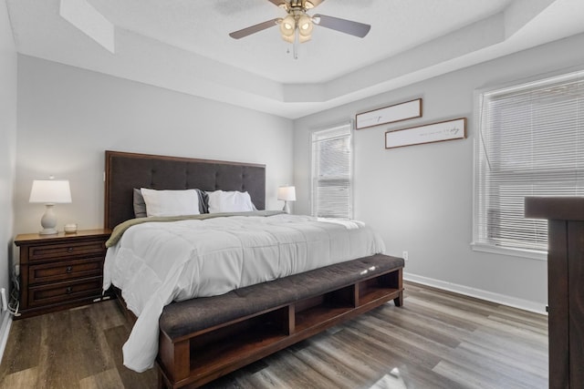 bedroom with ceiling fan, a raised ceiling, and hardwood / wood-style floors