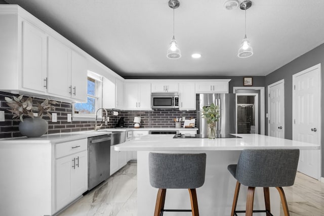 kitchen with decorative light fixtures, a center island, appliances with stainless steel finishes, decorative backsplash, and white cabinets