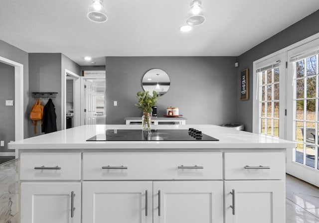 kitchen featuring a center island, black electric stovetop, and white cabinets