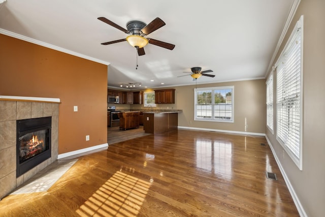 unfurnished living room with crown molding, ceiling fan, a fireplace, and dark hardwood / wood-style flooring