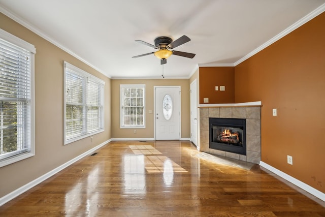 unfurnished living room with crown molding, ceiling fan, wood-type flooring, and a fireplace