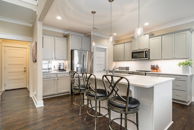 kitchen featuring sink, decorative light fixtures, appliances with stainless steel finishes, gray cabinets, and an island with sink