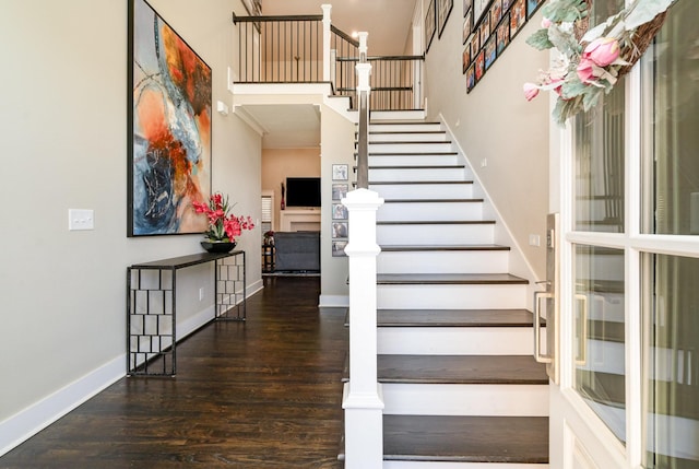 stairway with wood-type flooring and a high ceiling