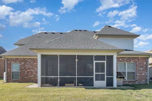 rear view of house featuring a sunroom and a lawn