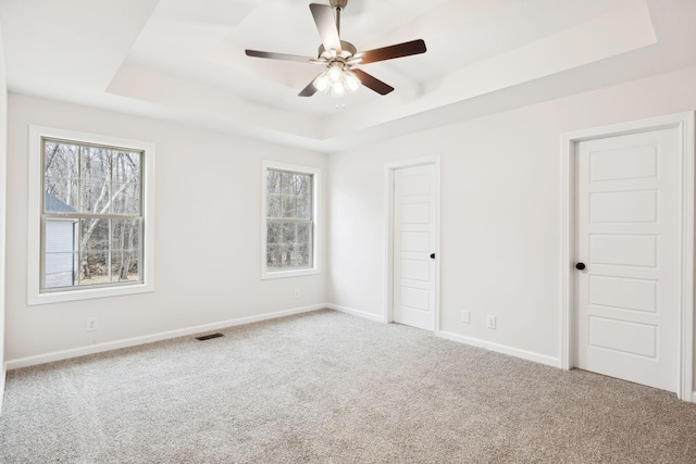 unfurnished bedroom with carpet floors, a raised ceiling, and ceiling fan