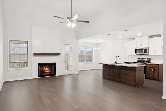 kitchen featuring lofted ceiling, sink, appliances with stainless steel finishes, white cabinetry, and decorative light fixtures