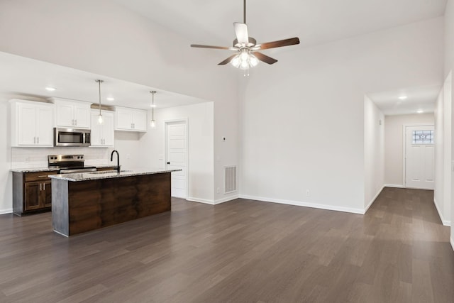 kitchen featuring sink, light stone counters, an island with sink, stainless steel appliances, and white cabinets