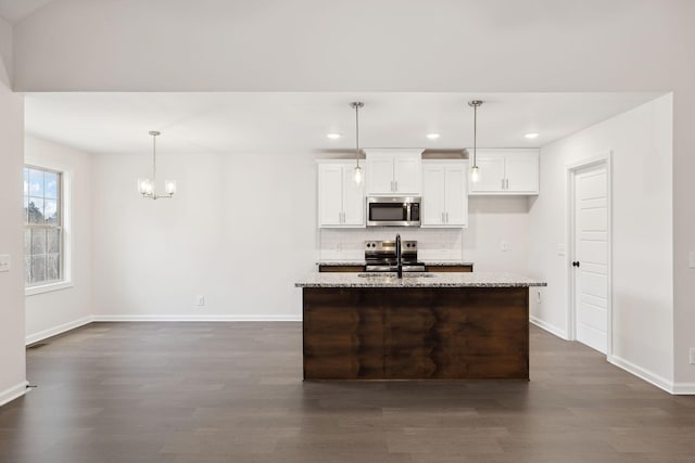 kitchen with sink, white cabinetry, an island with sink, stainless steel appliances, and light stone countertops