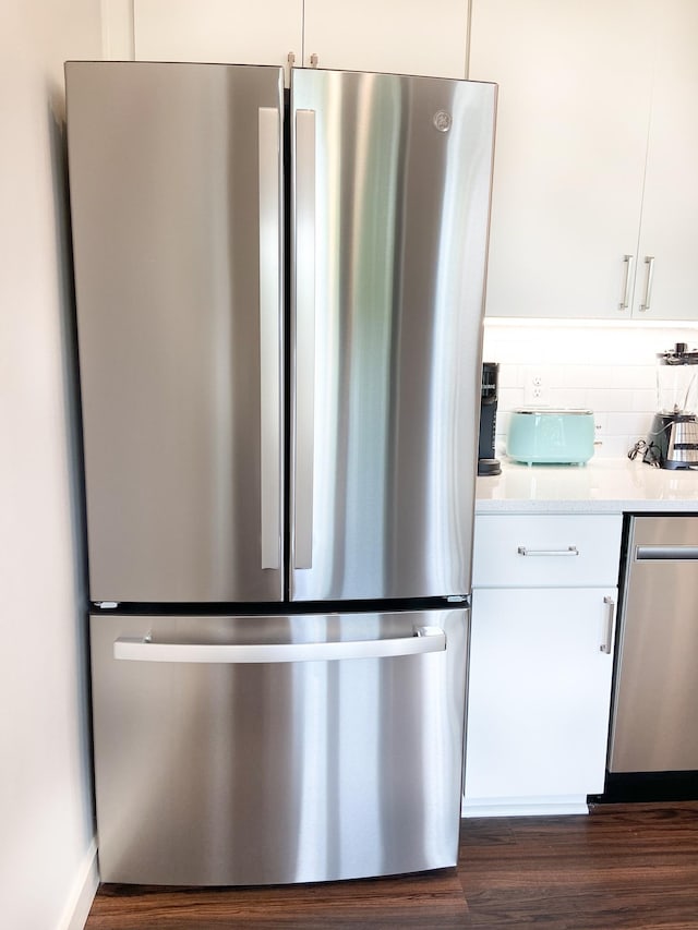 kitchen with dark wood-type flooring, appliances with stainless steel finishes, decorative backsplash, and white cabinets