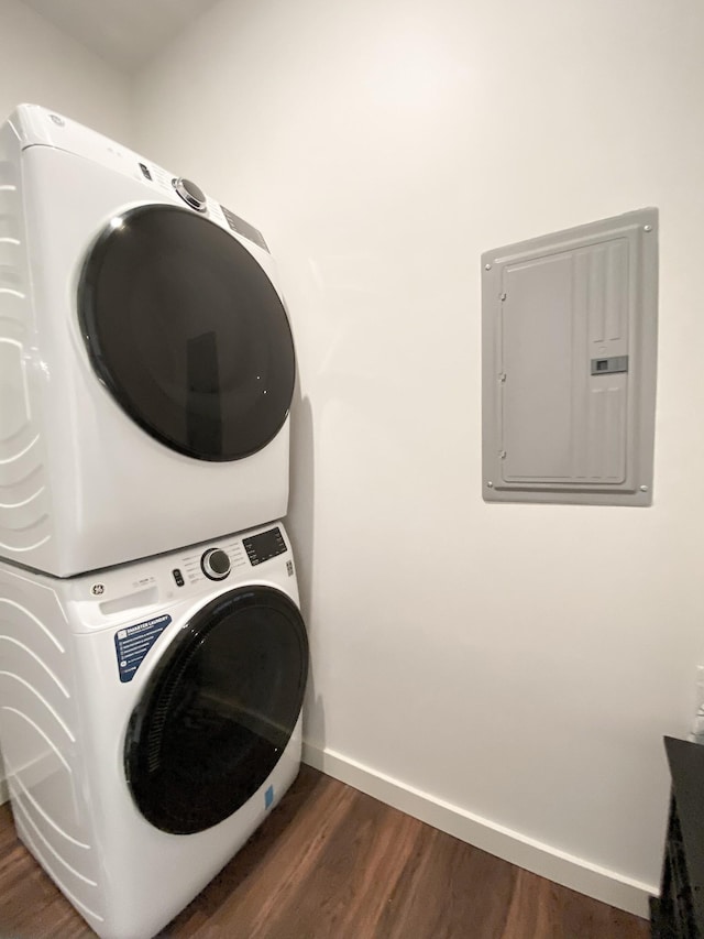 clothes washing area with stacked washer and dryer, dark hardwood / wood-style floors, and electric panel