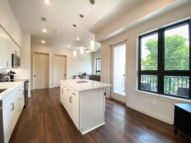 kitchen with hanging light fixtures, white cabinetry, appliances with stainless steel finishes, and a center island