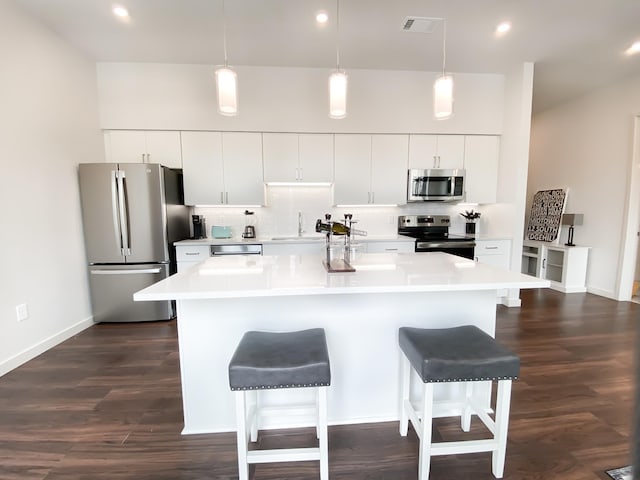 kitchen with sink, hanging light fixtures, a center island with sink, appliances with stainless steel finishes, and white cabinets