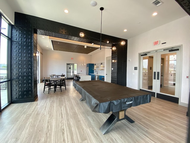 rec room featuring light hardwood / wood-style flooring, billiards, french doors, and bar area