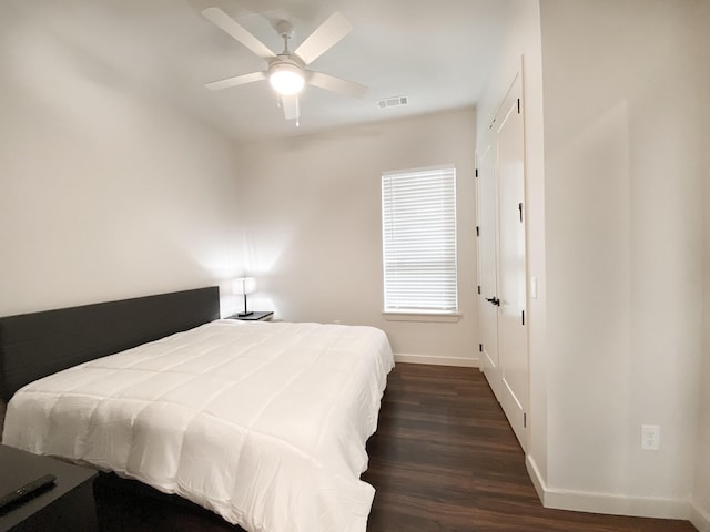 bedroom with dark hardwood / wood-style flooring and ceiling fan