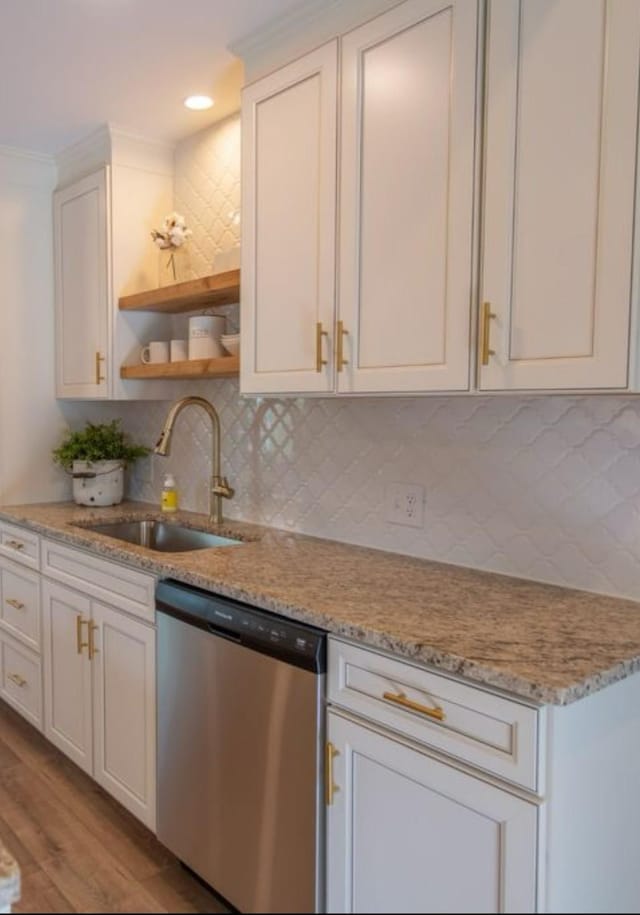 kitchen with light stone counters, sink, stainless steel dishwasher, and white cabinets