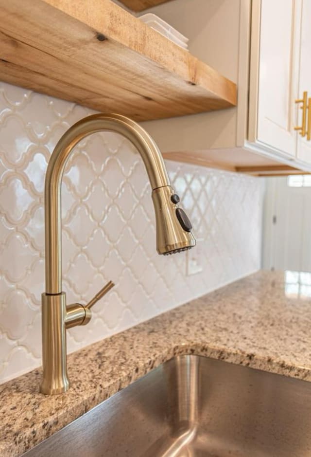 room details with light stone counters, sink, and backsplash