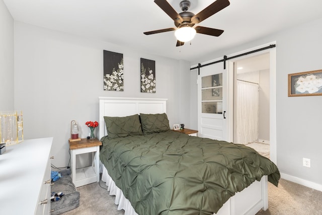 carpeted bedroom featuring a barn door and ceiling fan