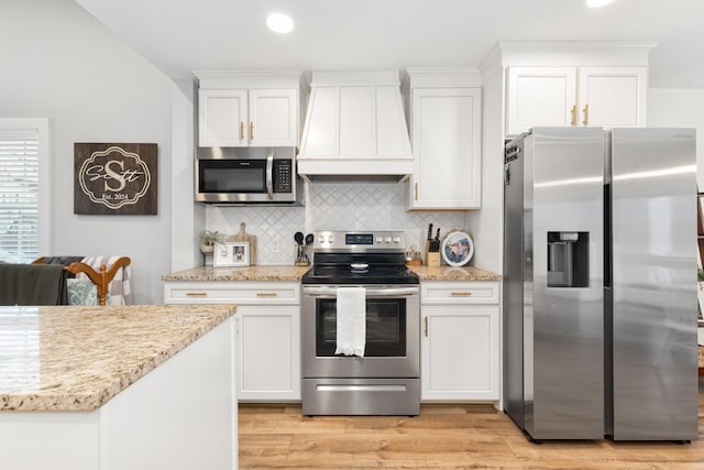 kitchen with white cabinetry, decorative backsplash, custom exhaust hood, light hardwood / wood-style floors, and stainless steel appliances