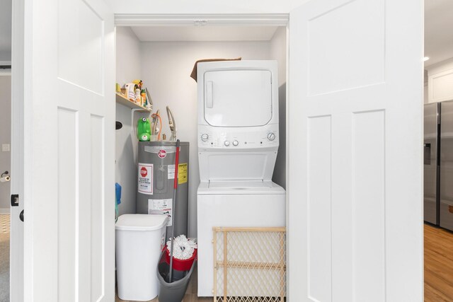 laundry room with hardwood / wood-style flooring, stacked washer and clothes dryer, and water heater