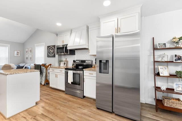 kitchen featuring custom exhaust hood, light hardwood / wood-style floors, white cabinets, and appliances with stainless steel finishes