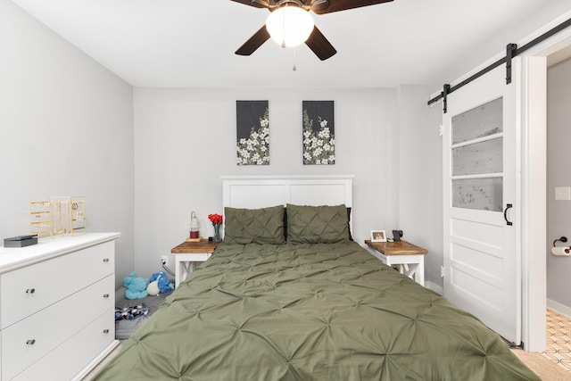 bedroom with ceiling fan and a barn door