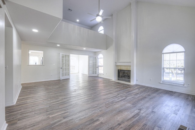 unfurnished living room with hardwood / wood-style flooring, high vaulted ceiling, ceiling fan, and french doors