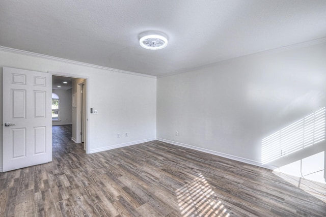 spare room featuring crown molding, dark wood-type flooring, and a textured ceiling