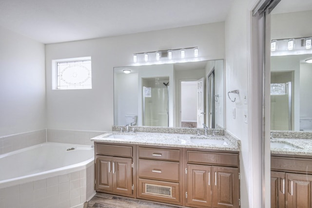 full bathroom with vanity, toilet, independent shower and bath, and hardwood / wood-style floors