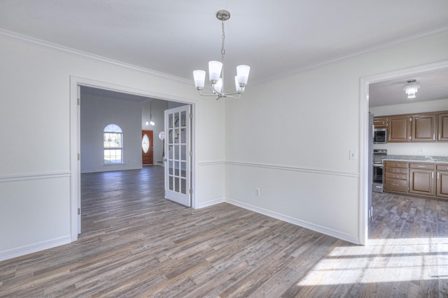 unfurnished dining area featuring hardwood / wood-style flooring, ornamental molding, and a chandelier