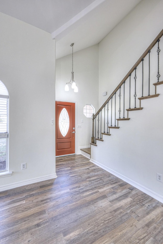 entryway featuring dark wood-type flooring, high vaulted ceiling, and a notable chandelier