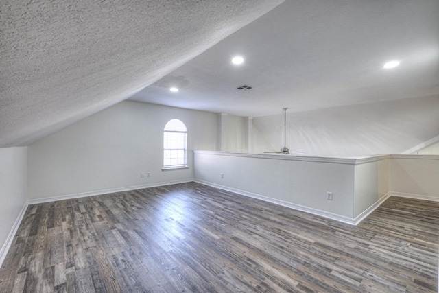 bonus room with ceiling fan, lofted ceiling, dark hardwood / wood-style flooring, and a textured ceiling