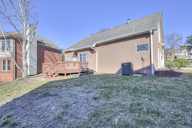 back of house with cooling unit, a deck, and a lawn