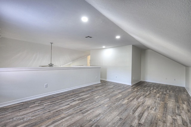 bonus room with dark wood-type flooring, ceiling fan, vaulted ceiling, and a textured ceiling