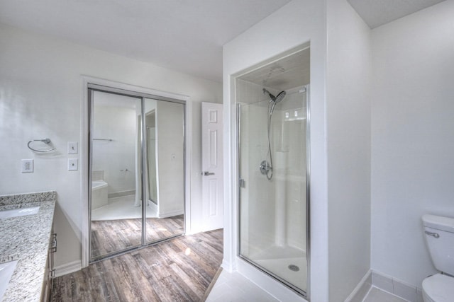 bathroom featuring a shower with door, wood-type flooring, vanity, and toilet