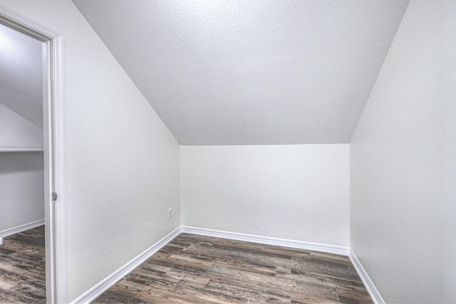 bonus room with dark hardwood / wood-style floors, vaulted ceiling, and a textured ceiling