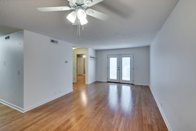 spare room with ceiling fan, light hardwood / wood-style flooring, french doors, and a textured ceiling