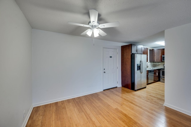 spare room with sink, ceiling fan, a textured ceiling, and light wood-type flooring