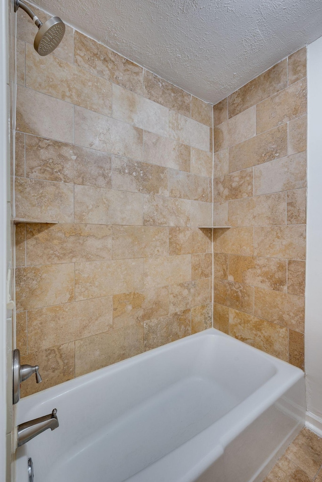 bathroom with tiled shower / bath combo and a textured ceiling