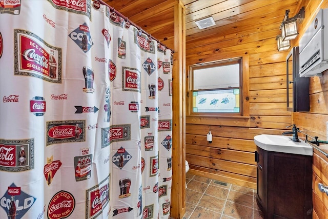 bathroom featuring gas water heater, wooden ceiling, wooden walls, and vanity