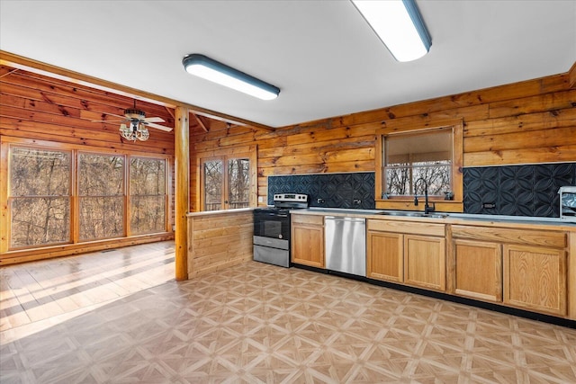 kitchen with appliances with stainless steel finishes, sink, ceiling fan, and wood walls