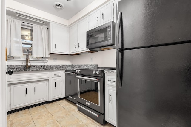 kitchen featuring white cabinetry, fridge, black electric range oven, and light tile patterned flooring